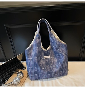 Blue tote bag with star patterns shown with a laptop and headphones in office setting