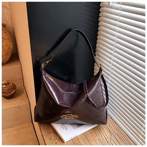 Dettaglio della borsa tote bordeaux vintage con logo ovale in metallo dorato lucido