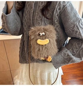 Close-up of brown monster plush bag with cartoon eyes and feet on fuzzy material