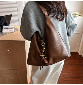 Detail view of large retro brown faux leather tote bag with wooden bead and tassel decor