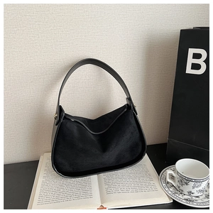 Detail of minimalist black faux suede hobo bag with sleek handle on a textured background