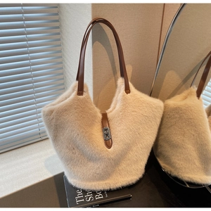 Detail of plush off-white tote bag featuring premium brown leather handles and metal lock