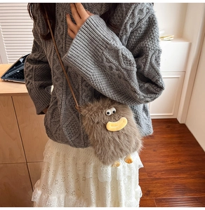 Close-up of a cute brown plush monster bag with big eyes and yellow mouth detail