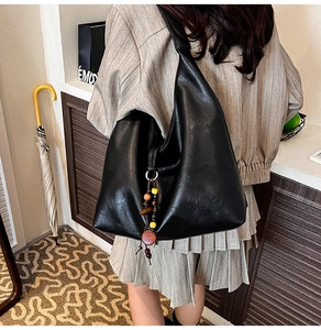 Detail showing back view of large black leather shoulder bag with beaded charm