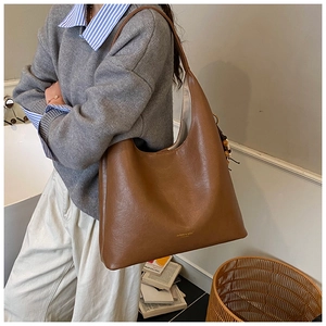 Grand sac cabas en cuir souple marron avec logo doré porté par un mannequin en intérieur