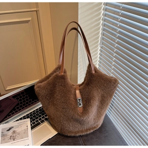 Detail of plush brown tote bag with leather straps and metal buckle in soft sunlight