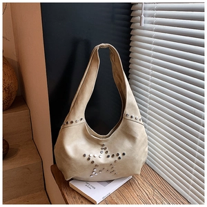 Close-up of beige vintage hobo bag with rivet star pattern on faux leather material