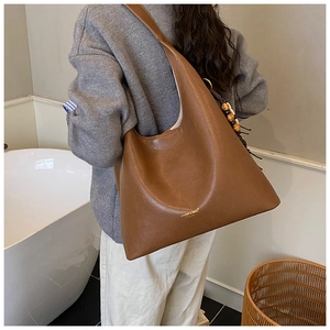 Détail du sac cabas en cuir marron avec breloque en perles de bois et logo de marque