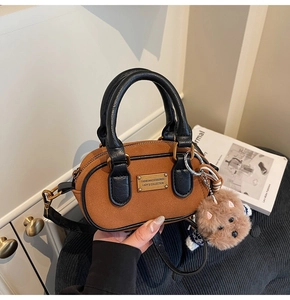 Dettaglio borsa Boston in camoscio marrone con placca dorata, manici e ciondolo orsetto