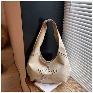 Detail of hobo bag with silver star-shaped rivet decoration on beige textured leather