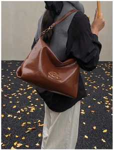 Dettaglio della borsa vintage in pelle cerata marrone con elegante logo dorato