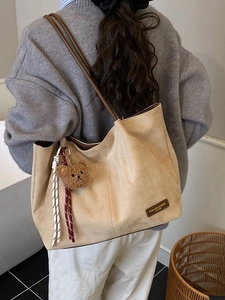 Beige suede tote bag with brown straps and cute bear charm shown on a female model