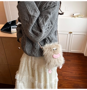 Detail shot of a cute beige plush monster crossbody bag with fun 3D facial features