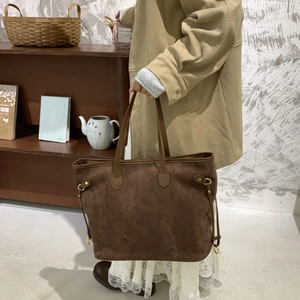 Detail of dark brown faux suede tote bag with leather straps and gold metal ring buckle