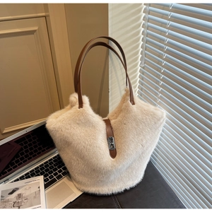 Detailed close-up of fluffy beige faux fur tote bag with brown leather handle and metal lock