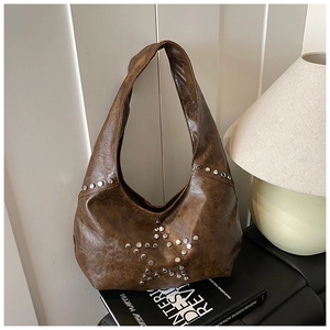 Detailed texture of brown vintage leather hobo bag with silver star-shaped metal rivets
