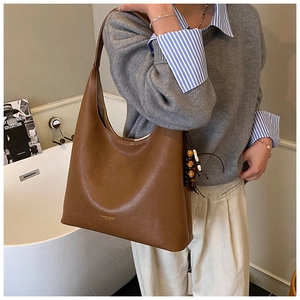Détail du sac Hobo marron caramel avec pompon en perles de bois et logo doré discret