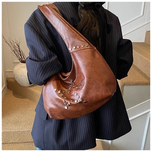 Detail of vintage brown shoulder bag with silver studs on textured leather finish