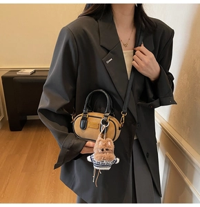 Dettaglio della mini borsa Boston con ciondolo di peluche e logo in metallo dorato
