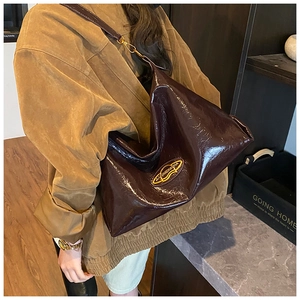 Dettaglio della borsa tote marrone scuro con finitura lucida e logo dorato elegante