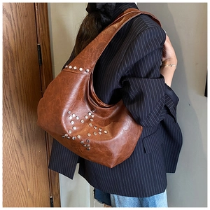 Detail showing the brown faux leather hobo bag with silver star rivets on the model
