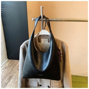 Détail d'un sac cabas en cuir noir avec logo de la marque sur le devant et texture naturelle