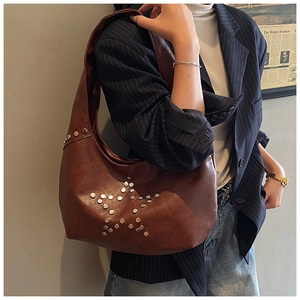 Brown vintage hobo bag featuring silver star rivets worn with a striped blazer