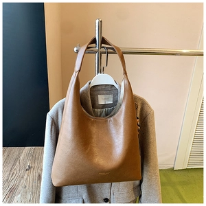 Gros plan sur la texture du sac hobo en similicuir marron avec logo doré élégant