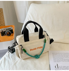Detalle del bolso Boston de nailon crema con cuerda verde y bordado naranja