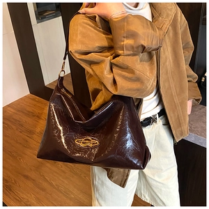 Dettaglio della borsa hobo in vernice marrone scuro lucida con logo e finiture in metallo oro
