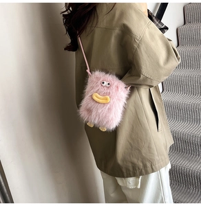 Close-up of pink fuzzy monster crossbody bag with cartoon eyes and yellow duck beak