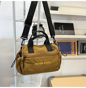Detalle del bolso bandolera de nailon marrón con bordado y cordón de ajuste ajustable