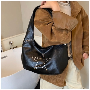 Detail of black leather hobo bag featuring silver star stud patterns on a punk style bag