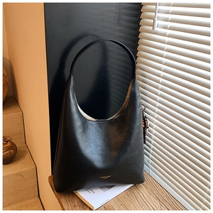 Détail du sac hobo en cuir noir texturé montrant le design minimaliste et le logo