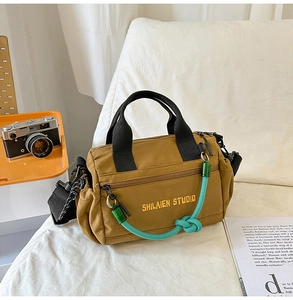 Detalle del bolso bandolera de nailon marrón con bordado amarillo y nudo de cuerda