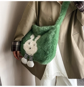 Détail d'un sac bandoulière en peluche verte avec un joli motif de lapin blanc doux