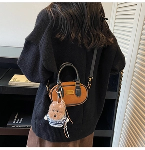 Detail of vintage brown textured Boston bag featuring a cute teddy bear charm and gold plaque
