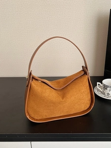 Sac hobo en daim caramel avec garniture en cuir et détails dorés dans un décor épuré