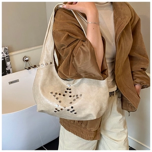 Detail of silver star studs on a beige faux leather hobo bag with a retro rivet pattern