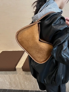 Sac bandoulière minimaliste en daim marron avec liseré en cuir porté par un modèle