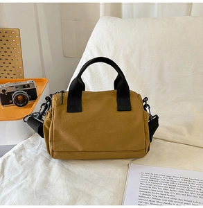Vista detallada del bolso bandolera de nailon amarillo con asas negras y bolsillo lateral