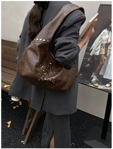 Brown vintage faux leather tote bag with silver star studs worn on a model's shoulder