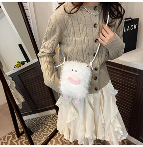 Detail of white plush monster crossbody bag with pink cartoon features worn by a model