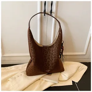 Gros plan sur un sac hobo léopard en daim avec un pendentif à pampilles de style ethnique
