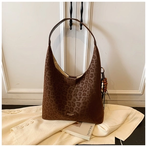 Détail du sac hobo léopard avec breloque en perles de bois et lettrage logo doré