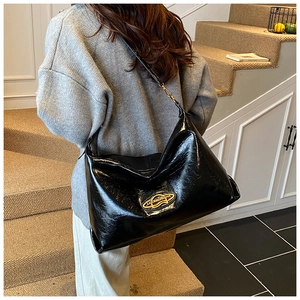 Dettaglio della borsa hobo nera lucida con logo ovale dorato sul pannello frontale
