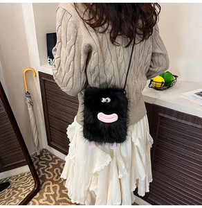 Detail of cute monster plush crossbody bag with pink feet on a soft cable knit sweater