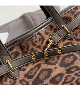 Gros plan du sac cabas léopard avec ferrures dorées mates et poignées en cuir marron