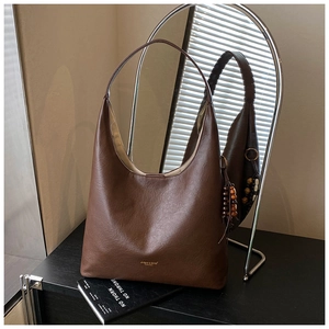 Gros plan d'un sac cabas marron avec logo doré et pendentif décoratif en perles de bois