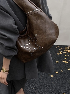 Vintage dark brown studded hobo bag with star rivet patterns for women on autumn street